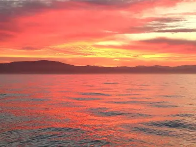 a sunset over the water with mountains in the background at Apartamentos Las Fuentes in Castropol