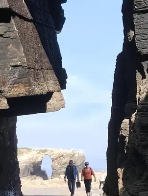 two men walking through a rock formation at Apartamentos Las Fuentes in Castropol