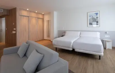 a bedroom with a white bed and a couch at Apartamentos Forum Ceao in Lugo