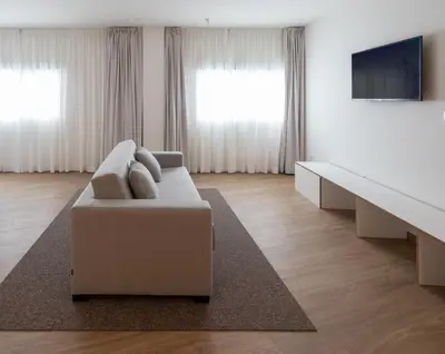 a white living room with a couch and a tv at Apartamentos Forum Ceao in Lugo