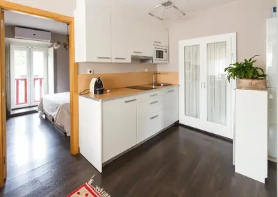 a kitchen with white cabinets and a bed in a room at O Remanso Dos Patos in Penalba