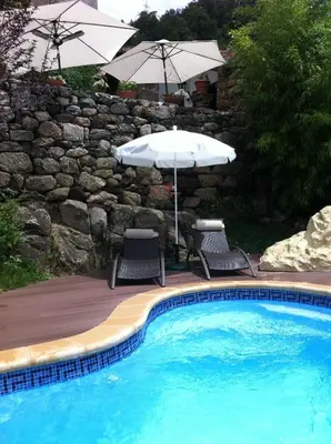 a swimming pool with two chairs and an umbrella at O Remanso Dos Patos in Penalba