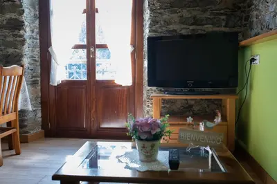 a living room with a tv and a coffee table at Apartamentos Rurales Las Mestas in Puenteciella