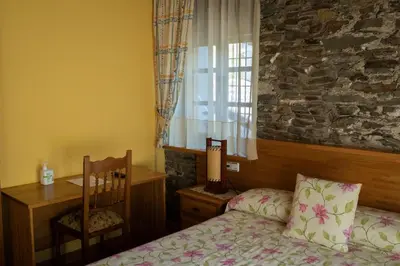 a bedroom with a bed and a chair and a window at Apartamentos Rurales Las Mestas in Puenteciella