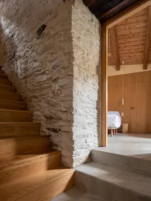 a staircase in a room with a stone wall at Fogar Mozárabe in Peñalba de Santiago