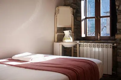 a bedroom with a bed with a mirror and a window at Fogar Mozárabe in Peñalba de Santiago