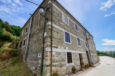 an old stone building with flowers in front of it at A Casoa in Santa Eulalia de Oscos