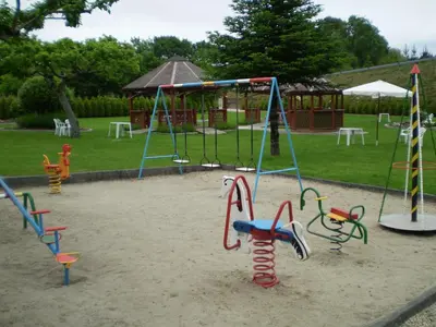 a playground with several playground equipment in the sand at Hostal La Casilla in Guitiriz