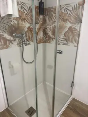 a shower with glass doors in a bathroom at Hostal As Margaritas in Santiago de Compostela