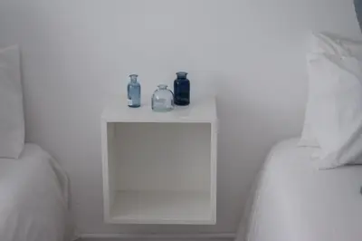 a white table with two bottles on it next to a bed at La Casa de Manuel in Portomarin