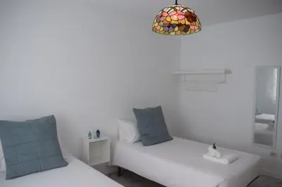 a white room with two beds and a chandelier at La Casa de Manuel in Portomarin
