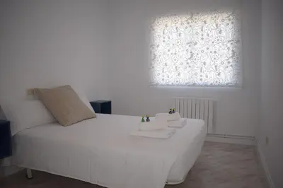 a white bed in a room with a window at La Casa de Manuel in Portomarin