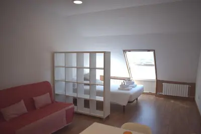 a living room with a bed and a red couch at La Casa de Manuel in Portomarin
