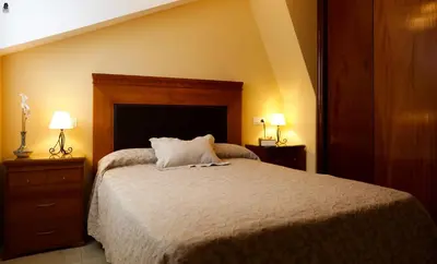 a bedroom with a bed with two night stands and two lamps at Viviendas Turisticas Tapia in Tapia de Casariego