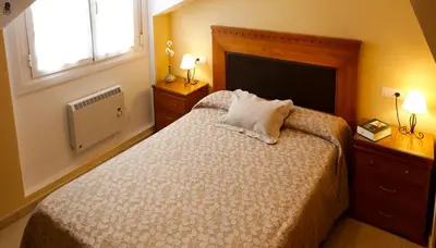 a bedroom with a bed and two lamps and a window at Viviendas Turisticas Tapia in Tapia de Casariego