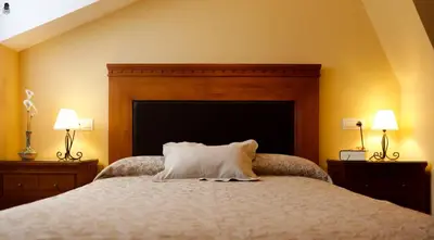 a bedroom with a bed with a headboard and two lamps at Viviendas Turisticas Tapia in Tapia de Casariego
