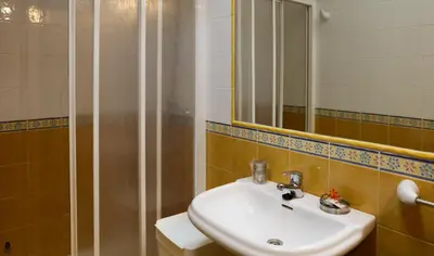 a bathroom with a sink and a mirror and a shower at Viviendas Turisticas Tapia in Tapia de Casariego