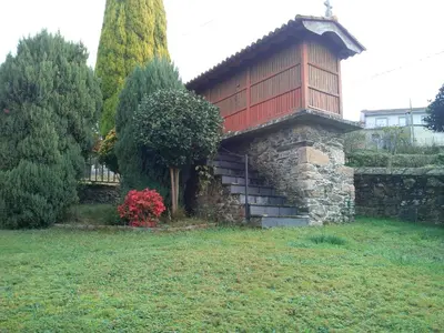 a building with a balcony on top of a yard at Casa Rural Oza dos Ríos in Oza dos Ríos