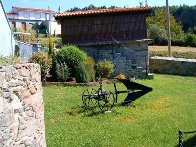 a garden cart sitting in the grass in a yard at Casa Rural Oza dos Ríos in Oza dos Ríos