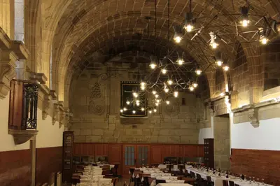 a large dining room with tables and chandeliers at Hospedería San Martín Pinario in Santiago de Compostela