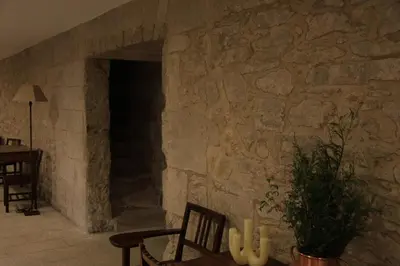 a stone wall with a fireplace with a table and chairs at Hospedería San Martín Pinario in Santiago de Compostela