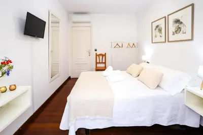 a white bedroom with a white bed and a tv at Pensión As Burgas in Caldas de Reis