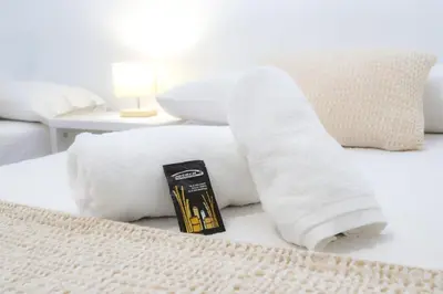 a roll of white towels sitting on a bed at Pensión As Burgas in Caldas de Reis