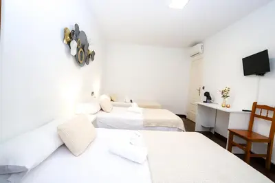 a hotel room with three beds and a desk at Pensión As Burgas in Caldas de Reis