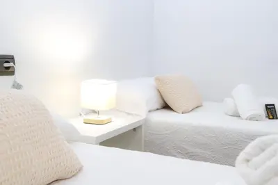 a bedroom with two beds and a table with a lamp at Pensión As Burgas in Caldas de Reis