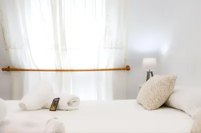 a bedroom with a white bed with a window at Pensión As Burgas in Caldas de Reis