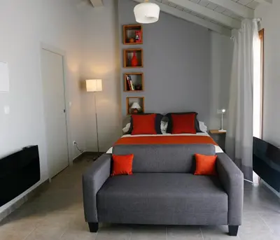 a bedroom with a bed and a couch with orange pillows at Galpon Boutique Aldea De Abaixo in Palas de Rei