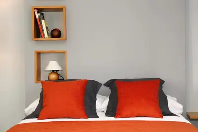 a bed with two red pillows and a lamp at Galpon Boutique Aldea De Abaixo in Palas de Rei