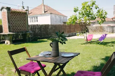 a wooden table with pink cushioned chairs in a yard at Galpon Boutique Aldea De Abaixo in Palas de Rei