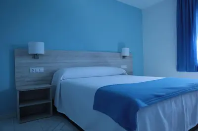 a bedroom with two beds and a blue light at Hotel Playa de las Catedrales in Reinante
