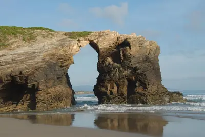 an arch in a rock formation in the ocean at Hotel Playa de las Catedrales in Reinante