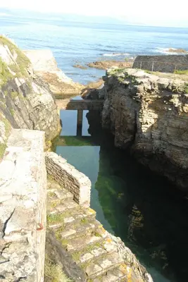 a stone bridge over a body of water near the ocean at Hotel Playa de las Catedrales in Reinante
