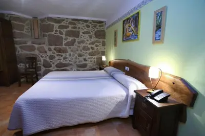 a bedroom with a large bed and a stone wall at Hotel Rústico Casa Franco in Adelán