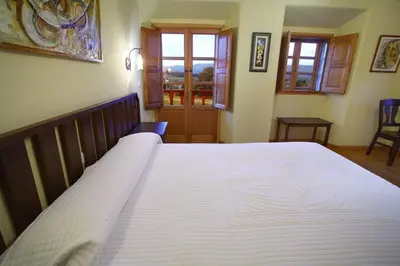 a bedroom with a large white bed in a room at Hotel Rústico Casa Franco in Adelán