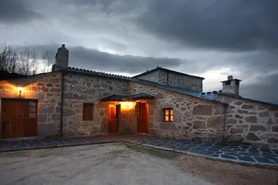 an old stone house with its door open on a cloudy day at Hotel Rústico Casa Franco in Adelán
