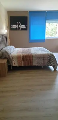 a bed in a bedroom with a blue window at Hotel O Camiño in O Barco de Valdeorras