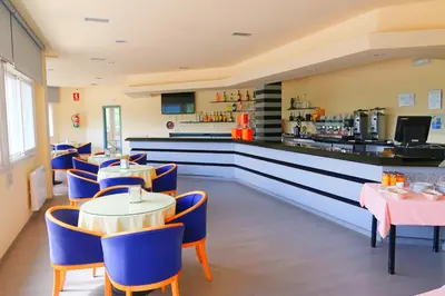 a restaurant with tables and blue chairs and a counter at Hotel O Camiño in O Barco de Valdeorras