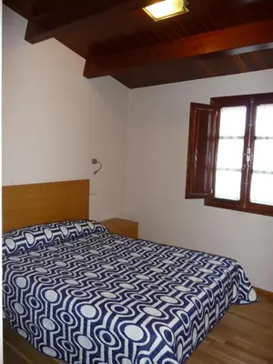 a bedroom with a bed with a blue and white comforter at Hortas P.R. in Santiago de Compostela