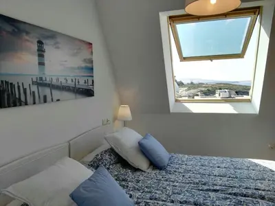 a bedroom with a bed with blue pillows and a window at San Ciprian Atico Playa by I Love Norte in San Ciprián