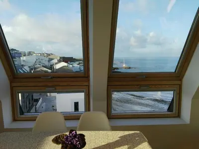 a dining room with three windows with a view of the ocean at San Ciprian Atico Playa by I Love Norte in San Ciprián