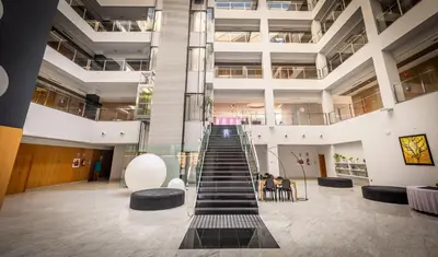 a spiral staircase in a building with tables and chairs at Hotel Ciudad de Ponferrada, Ascend Hotel Collection in Ponferrada