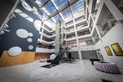 a lobby with a staircase and tables and chairs at Hotel Ciudad de Ponferrada, Ascend Hotel Collection in Ponferrada