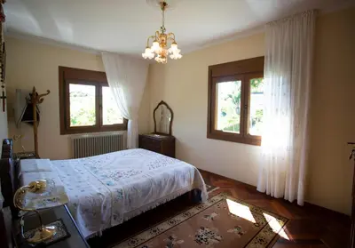 a bedroom with a bed and two windows and a chandelier at Villa con piscina en Pantòn Ribeira Sacra Galicia Ideal para familias in Pantón