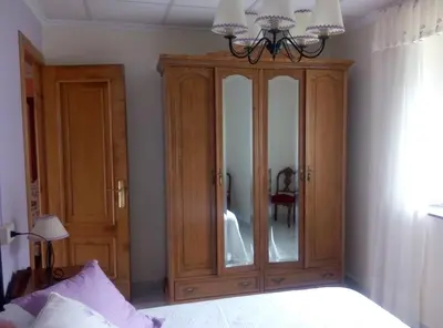 a bedroom with a wooden cabinet with a mirror at Vivienda de Uso Turístico Carballo Blanco 2 in Barral