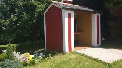 a small red and white shed in a yard at Vivienda de Uso Turístico Carballo Blanco 2 in Barral