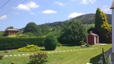 a garden with a small red shed in the grass at Vivienda de Uso Turístico Carballo Blanco 2 in Barral